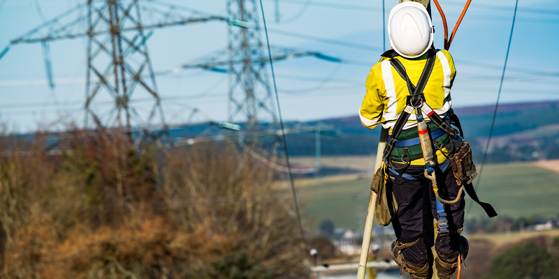 Engineer climbing pole with towers in background